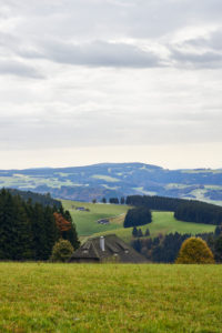 view to hills, forests, farms and pastures, sky with clouds