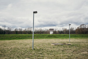 old watchtower, abandoned and weathered on a meadow with lamppost, trees, sky