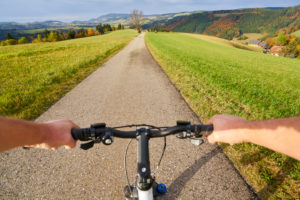 Hands on a handlebar of a bicycle with panoramic, Black Forest, bird's-eye view