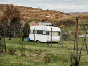 old caravan in a meadow, vineyards with vines in the background in autumn