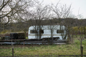 old caravan with boards on a meadow, vineyards in the background in autumn