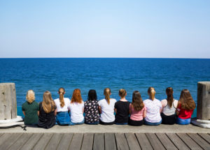 A group of girls sit next to each other on the pier and look at the sea, Heligoland, Schleswig-Holstein, Germany A group of girls sit next to each other on the pier and look at the sea, Heligoland, Schleswig-Holstein, Germany