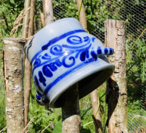 Alter Steingut-Topf auf dem Zaun als Gartendekoration Alter Steingut-Topf auf dem Zaun als Gartendekoration