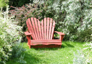 Roter Adirondack Chair in Herzform im Garten Roter Adirondack Chair in Herzform im Garten