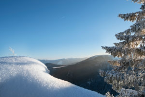 Snow-covered tree and rocks in wintry landscape with a view of the valley in front of sunny, blue sky in the Vosges Mountains, France Snow-covered tree and rocks in wintry landscape with a view of the valley in front of sunny, blue sky in the Vosges Mountains, France