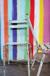 two old metal chairs with peeling paint against a colorful striped wall two old metal chairs with peeling paint against a colorful striped wall