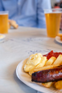 Plate with sausage and chips red and white, with beer from plastic cups Plate with sausage and chips red and white, with beer from plastic cups