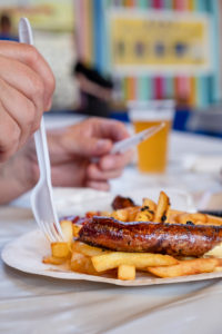 Bratwurst and fries are eaten with plastic cutlery Bratwurst and fries are eaten with plastic cutlery