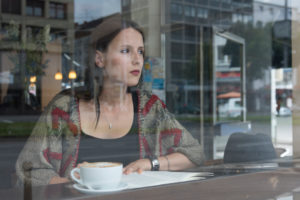 Young woman behind window while reading in the café, thoughtful, semi-portrait Young woman behind window while reading in the café, thoughtful, semi-portrait