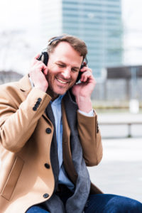 Businessman hears outside music with earphones, half portrait Businessman hears outside music with earphones, half portrait