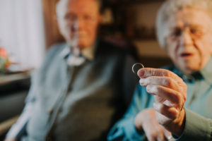 older couple, woman holds wedding ring into camera