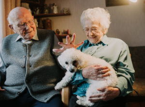 older couple with poodle in own home
