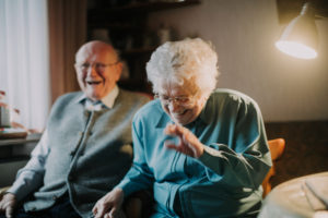 older couple sits laughingly in the living room