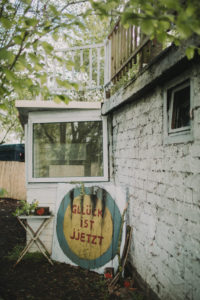 Old decayed garden house with the inscription 'Glück ist Jetzt' (Happiness is now) 