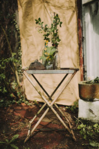 Garden table with glasses, bottle, flowers and ivy