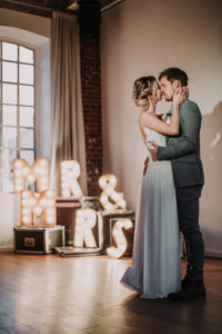Happy bridal couple, closed eyes, standing, hug, decoration, illuminated letters,