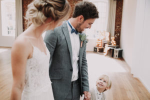 Bridal couple and boy holding hands, happy,