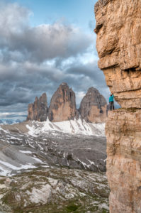 Drei Zinnen, Dolomites, Bolzano province, South Tyrol, Italy. A mountain climber admires the mountain panorama on an exposed rock band Drei Zinnen, Dolomites, Bolzano province, South Tyrol, Italy. A mountain climber admires the mountain panorama on an exposed rock band
