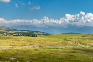 Villanders, Provinz Bozen, Südtirol, Italien. Almhütten auf der Villanderer Alm mit Blick zu den Dolomiten mit Peitlerkofel und Geislerspitzen Villanders, Provinz Bozen, Südtirol, Italien. Almhütten auf der Villanderer Alm mit Blick zu den Dolomiten mit Peitlerkofel und Geislerspitzen