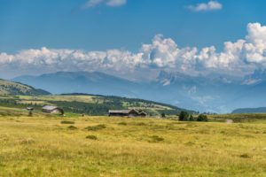 Villanders, Provinz Bozen, Südtirol, Italien. Almhütten auf der Villanderer Alm mit Blick zu den Dolomiten mit Peitlerkofel und Geislerspitzen Villanders, Provinz Bozen, Südtirol, Italien. Almhütten auf der Villanderer Alm mit Blick zu den Dolomiten mit Peitlerkofel und Geislerspitzen