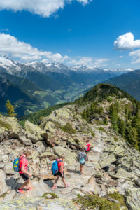 Sand in Taufers, Bolzano Province, South Tyrol, Italy. Hikers on the panorama trail in the Speikboden hiking area, in the background the Ahrntal with the Zillertal Alps Sand in Taufers, Bolzano Province, South Tyrol, Italy. Hikers on the panorama trail in the Speikboden hiking area, in the background the Ahrntal with the Zillertal Alps