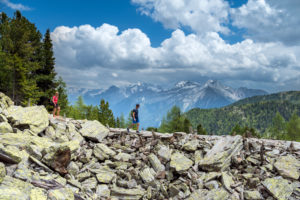 Sand in Taufers, Bolzano Province, South Tyrol, Italy. Hikers on the panorama trail in the Speikboden hiking area. In the background the summits of the Durreck group Sand in Taufers, Bolzano Province, South Tyrol, Italy. Hikers on the panorama trail in the Speikboden hiking area. In the background the summits of the Durreck group