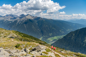 Sand in Taufers, Bolzano Province, South Tyrol, Italy. Hikers on the panorama path in the Speikboden hiking area with a deep view of the Tauferer Tal Sand in Taufers, Bolzano Province, South Tyrol, Italy. Hikers on the panorama path in the Speikboden hiking area with a deep view of the Tauferer Tal