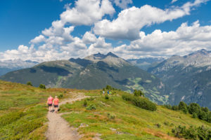 Sand in Taufers, Provinz Bozen, Südtirol, Italien. Wanderer auf dem Panoramaweg im Wandergebiet Speikboden. Im Hintergrund links ddie Durreckgruppe und rechts die Rieserfernegruppe Sand in Taufers, Provinz Bozen, Südtirol, Italien. Wanderer auf dem Panoramaweg im Wandergebiet Speikboden. Im Hintergrund links ddie Durreckgruppe und rechts die Rieserfernegruppe