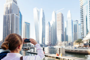 Dubai skyscrapers with Dubai Marina, female tourist taking a picture