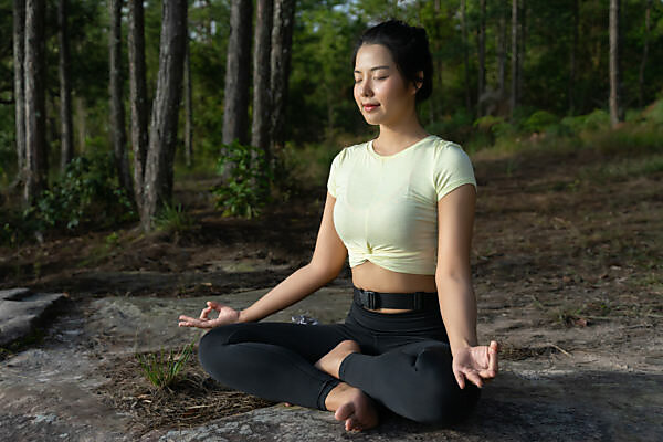 Attractive Woman in Yoga Pants and Top Sitting in Forest Taking
