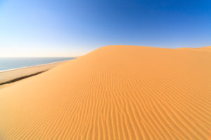 Sand dunes modeled by wind meet the Atlantic Ocean Walvis Bay Namib Desert Erongo Region Namibia Southern Africa Sand dunes modeled by wind meet the Atlantic Ocean Walvis Bay Namib Desert Erongo Region Namibia Southern Africa