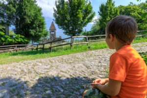 Child on footpath admires the Abbey of San Pietro in Vallate Piagno Sondrio province Lower Valtellina Lombardy Italy Europe Child on footpath admires the Abbey of San Pietro in Vallate Piagno Sondrio province Lower Valtellina Lombardy Italy Europe