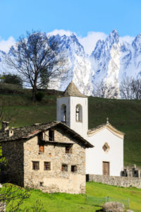 Alpine church and green meadows framed by the snowy peaks in spring Daloo Chiavenna Valley Valtellina Lombardy Italy Europe Alpine church and green meadows framed by the snowy peaks in spring Daloo Chiavenna Valley Valtellina Lombardy Italy Europe