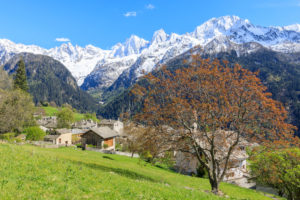 View of Soglio between meadows and snowy peaks in spring Maloja canton of Graubunden Engadin Bregaglia Valley Switzerland Europe View of Soglio between meadows and snowy peaks in spring Maloja canton of Graubunden Engadin Bregaglia Valley Switzerland Europe