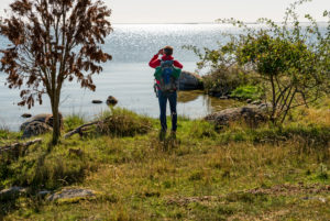 Mann mit Rucksack fotografiert aufs weite Meer hinaus. Mann mit Rucksack fotografiert aufs weite Meer hinaus.
