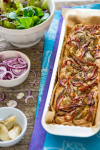 Foccacia frisch aus dem Ofen, in einer rechteckigen Tarteform, mit grünem Salat, extra roten Zwiebeln und Artischocken Foccacia frisch aus dem Ofen, in einer rechteckigen Tarteform, mit grünem Salat, extra roten Zwiebeln und Artischocken