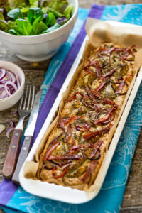 Foccacia frisch aus dem Ofen, in einer rechteckigen Tarteform, mit grünem Salat, extra roten Zwiebeln und Artischocken Foccacia frisch aus dem Ofen, in einer rechteckigen Tarteform, mit grünem Salat, extra roten Zwiebeln und Artischocken