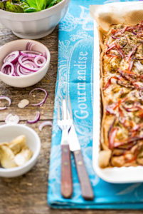 Foccacia frisch aus dem Ofen, in einer rechteckigen Tarteform, mit grünem Salat, extra roten Zwiebeln und Artischocken Foccacia frisch aus dem Ofen, in einer rechteckigen Tarteform, mit grünem Salat, extra roten Zwiebeln und Artischocken