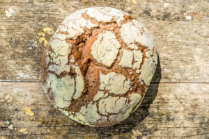Runder, frisch gebackener Brotlaib von oben, Hintergrund verwittertes Holz Runder, frisch gebackener Brotlaib von oben, Hintergrund verwittertes Holz