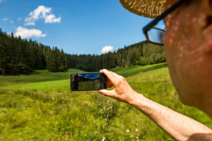 Mann fotografiert Landschaft mit dem Smartphone, auf dem Display ist die Landschaft zu sehen, Bild im Bild Mann fotografiert Landschaft mit dem Smartphone, auf dem Display ist die Landschaft zu sehen, Bild im Bild