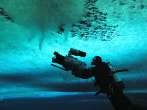 Cameraman, Didier Noirot, filming the formation of 'brinicles' (brine icicles or ice stalactites) under the ice, Ross Sea, McMurdo Sound, Antarctica. 