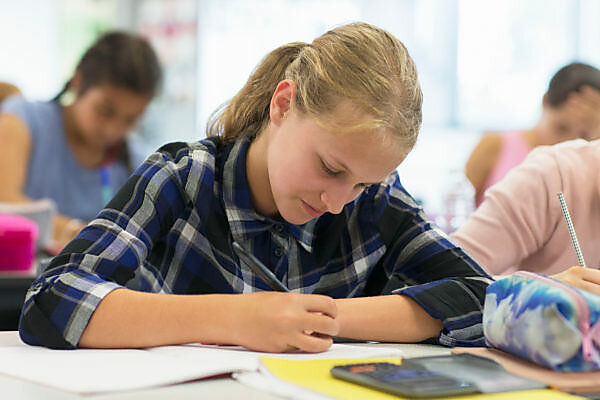 Bildagentur | mauritius images | Focused junior high school student doing  homework in classroom