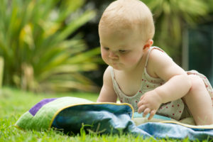 Baby sitting on blanket outdoors