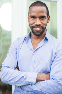 Man smiling with arms folded across chest, portrait