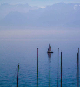 Sailing boat on Lake Geneva and mountains in the background