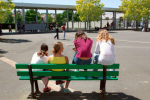 44. Basse Goulaine, Goulaine secondary school, playground, four teenage girls with their backs to a bench, two of them sitting on the backrest.