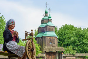 Kiev (Kyiv), Museum of Folk Architecture and Folkways of Ukraine in Pyrohiv, Zarubincy village church, wooden church, woman at spinning wheel in Kyiv, Ukraine Kiev (Kyiv), Museum of Folk Architecture and Folkways of Ukraine in Pyrohiv, Zarubincy village church, wooden church, woman at spinning wheel in Kyiv, Ukraine
