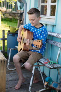 Boy playing guitar in front of garden house Boy playing guitar in front of garden house