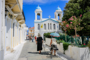 Andros town, Andros island, Cyclades, Greece - Locals and tourists walk through the narrow, colorful streets of the old town of the capital Andros (Chora). Andros town, Andros island, Cyclades, Greece - Locals and tourists walk through the narrow, colorful streets of the old town of the capital Andros (Chora).