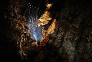 Cave explorer in dripping water of a cave Cave explorer in dripping water of a cave